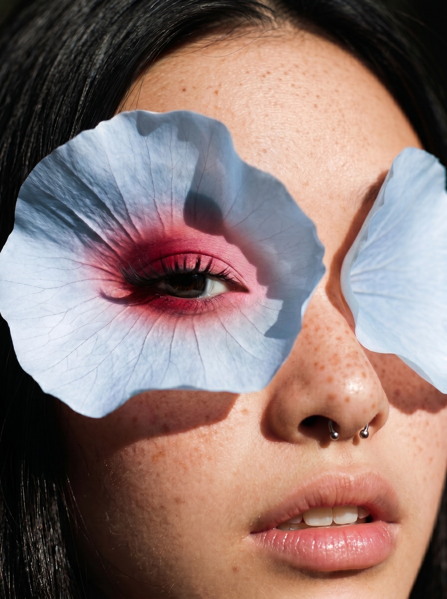 A close-up portrait with blue flower petals framing one eye.
